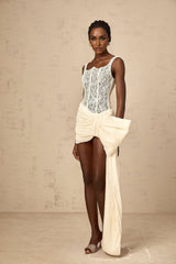 A short sleeveless mini dress in neutral tones featuring a bowknot detail and floral lace pattern with a pencil skirt silhouette