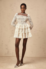 A short sleeveless mini dress in neutral tones featuring delicate floral embroidery patterns throughout the fabric