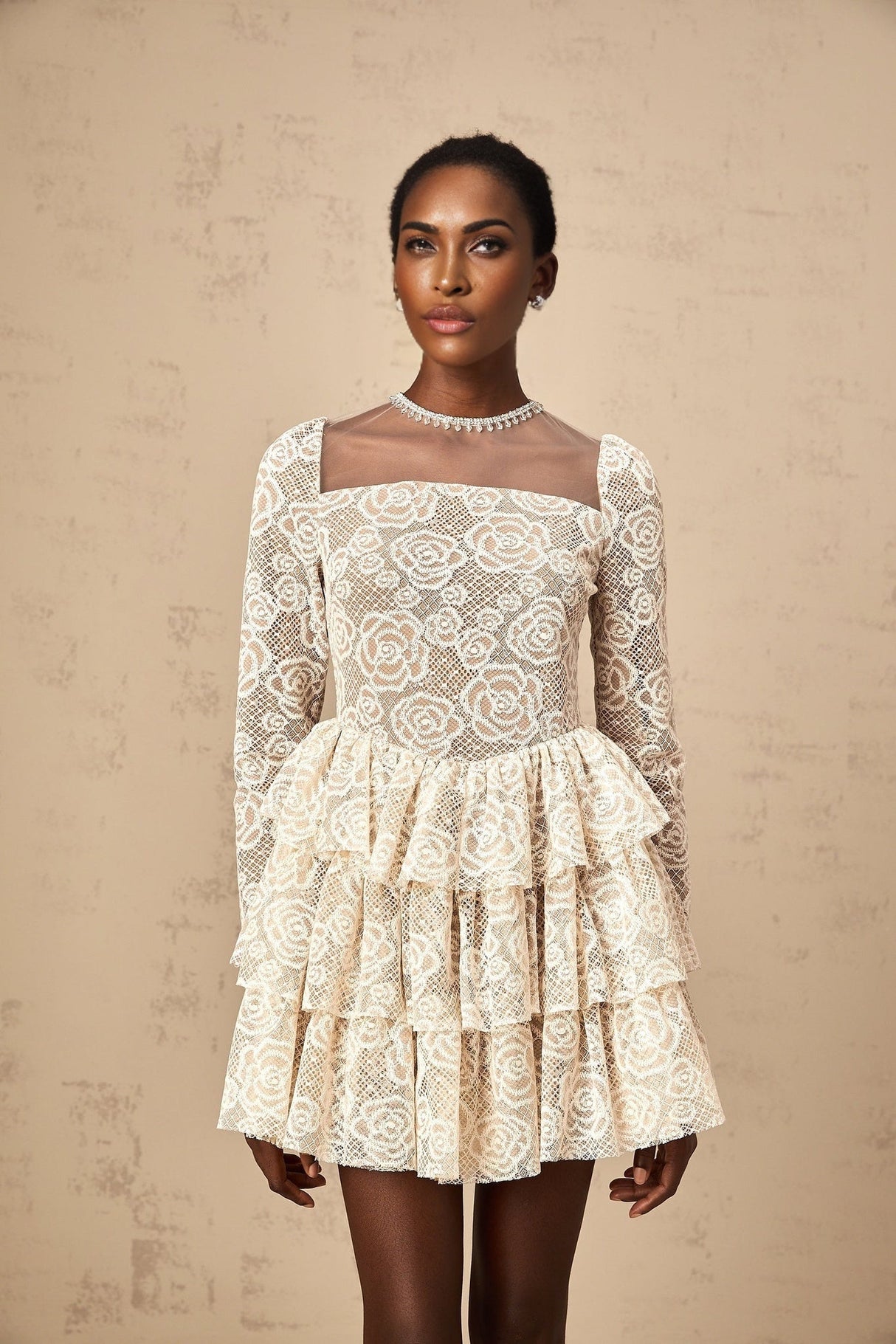 A short sleeveless mini dress in neutral tones featuring delicate floral embroidery throughout the fabric