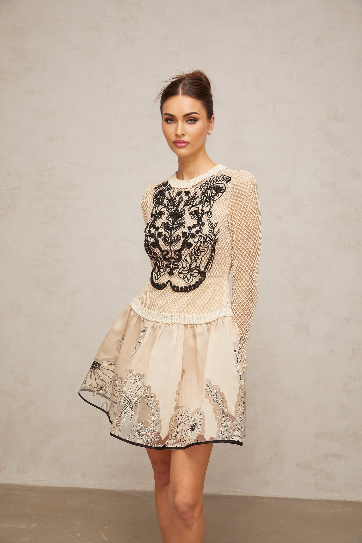 A short sleeveless mini dress with a floral jacquard pattern featuring contrasting color floral appliques and a fitted silhouette