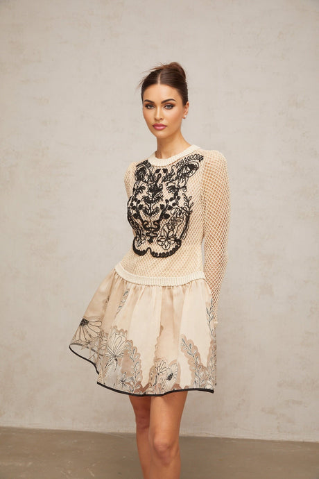 A short sleeveless mini dress with a floral jacquard pattern featuring contrasting color floral appliques and a fitted silhouette