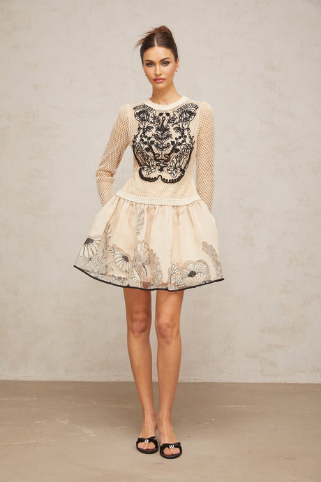 A short sleeveless mini dress with a floral jacquard pattern featuring contrasting color floral appliques for added texture and visual interest