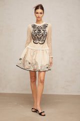 A short sleeveless mini dress with a floral jacquard pattern featuring contrasting color floral appliques on the bodice