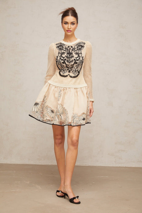 A short sleeveless mini dress with a floral jacquard pattern featuring contrasting color floral appliques on the bodice