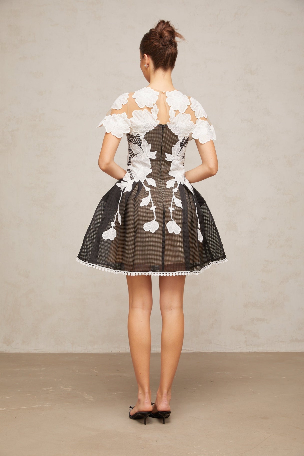 A short sleeveless mini dress with colorblocked sections featuring floral embroidery designs in contrasting colors creating a vibrant and feminine look