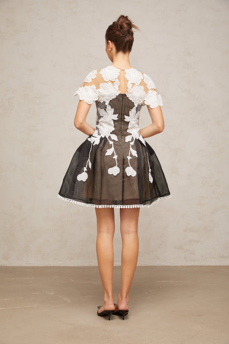 A short sleeveless mini dress with colorblocked sections featuring floral embroidery designs in contrasting colors creating a vibrant and feminine look