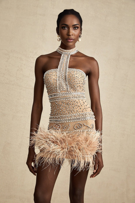A short sleeveless mini dress with crystal embellishments and feather trim along the hemline in a light color likely white or cream