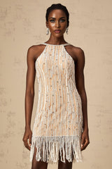 A short sleeveless mini dress with embellishments and fringe detailing along the hemline featuring a light colored fabric and a fitted silhouette
