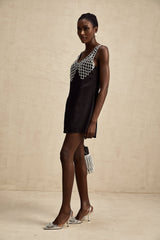 A short sleeveless satin mini dress in a light color adorned with sparkling crystal embellishments throughout the bodice and skirt