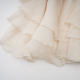 A short sleeveless tiered mini dress in neutral tones with floral applique details throughout the fabric