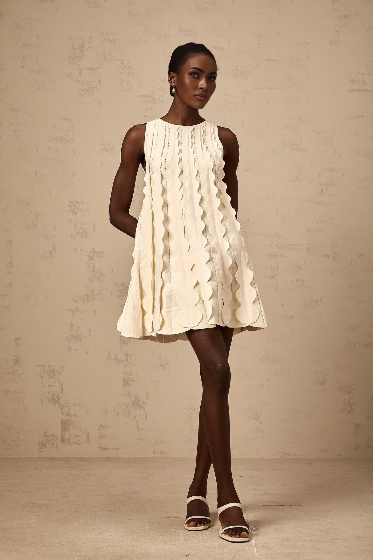 A short sleeveless white mini dress with wavy details along the edges named Axelle