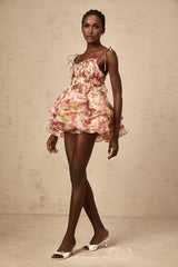 A short tiered mini dress with a strawberry print pattern featuring a light background and red strawberries scattered throughout the fabric