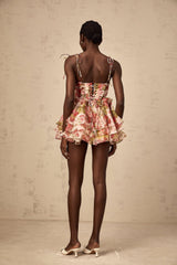 A short tiered mini dress with a strawberry print pattern featuring a light background and red strawberries scattered throughout the fabric