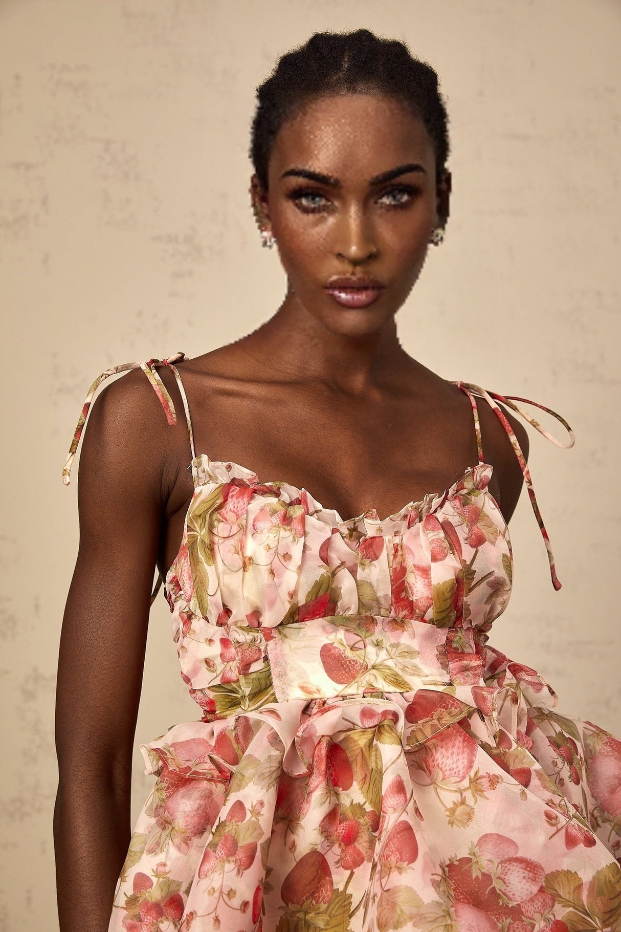 A short tiered mini dress with a strawberry print pattern featuring ruffled layers and a feminine silhouette