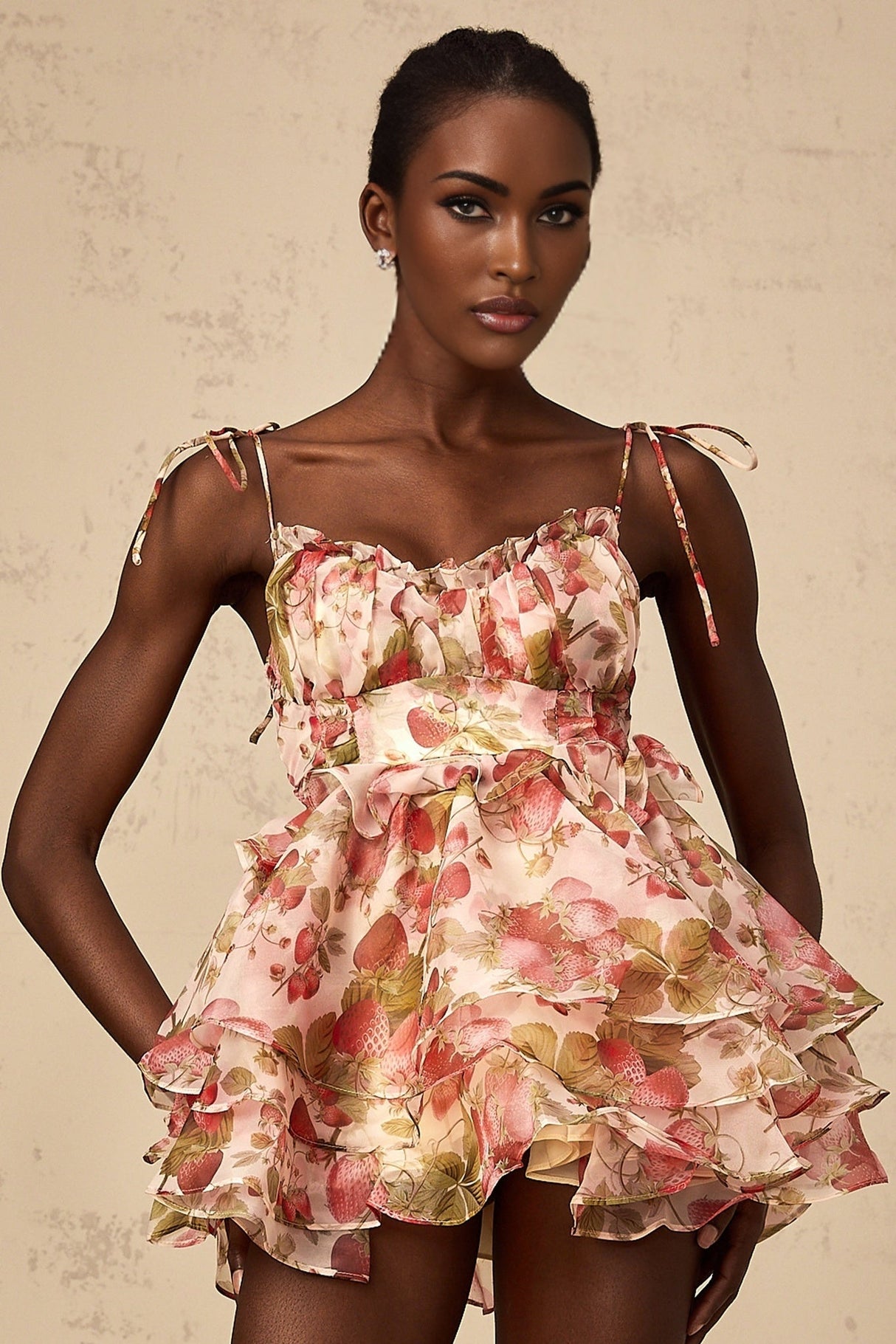 A short tiered mini dress with a vibrant strawberry print pattern featuring a red and green color scheme on a light background