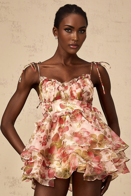 A short tiered mini dress with a vibrant strawberry print pattern featuring a red and green color scheme on a light background