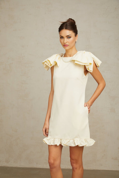 A short white dress with ruffles and a bow detail featuring a mini length design