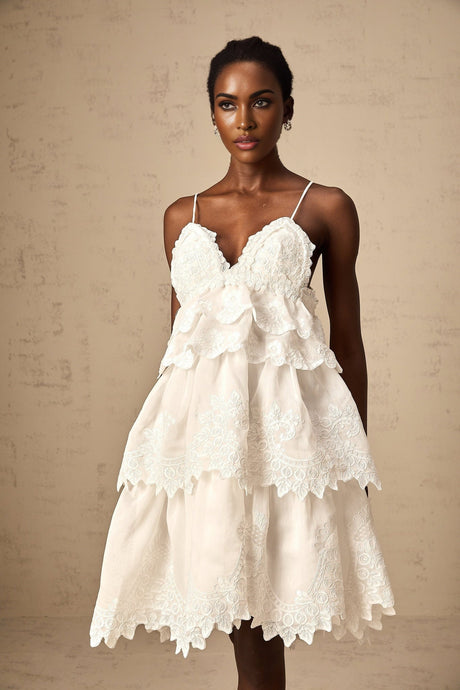A short white dress with tiered ruffles made of delicate guipure lace featuring a mini length and feminine silhouette