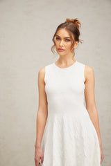 A short white knitted mini dress with a star pattern featuring a jasmine design worn by a model against a plain background
