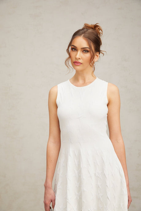 A short white knitted mini dress with a star pattern featuring a jasmine design worn by a model against a plain background