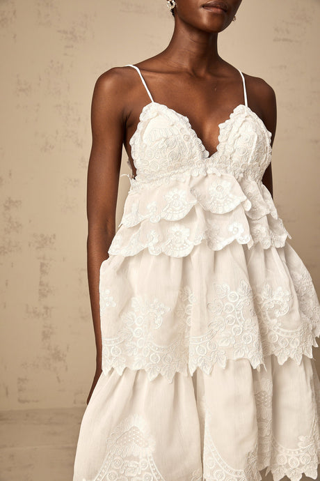 A short white lace dress with tiered layers and intricate guipure patterns featuring a mini length and delicate feminine design