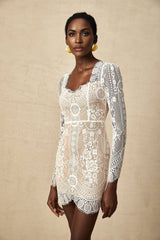 A short white lace mini dress with scalloped edges at the hem featuring delicate floral patterns and a fitted silhouette