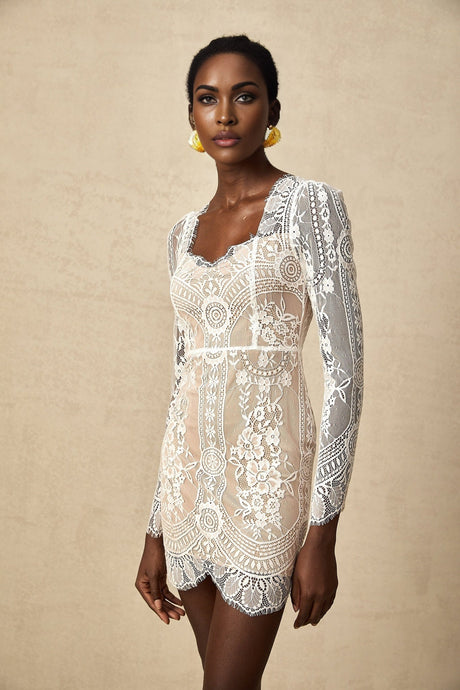 A short white lace mini dress with scalloped edges at the hem featuring delicate floral patterns and a fitted silhouette