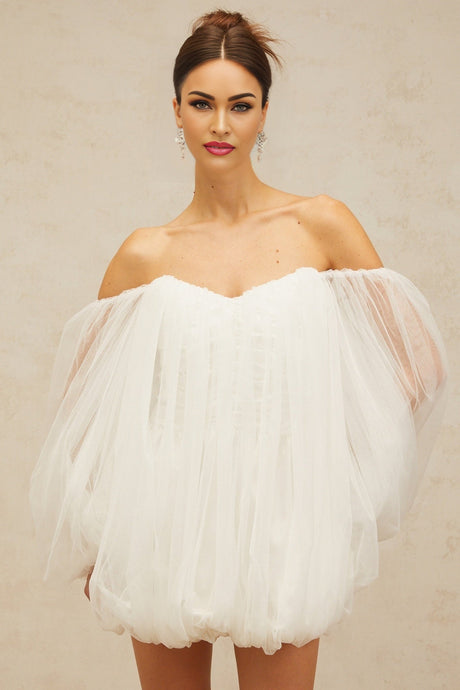 A short white layered dress with a puffy tulle skirt and bubblelike texture worn by a model against a plain background