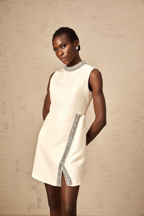 A short white mini dress adorned with crystal embellishments featuring a feminine silhouette and sparkly details
