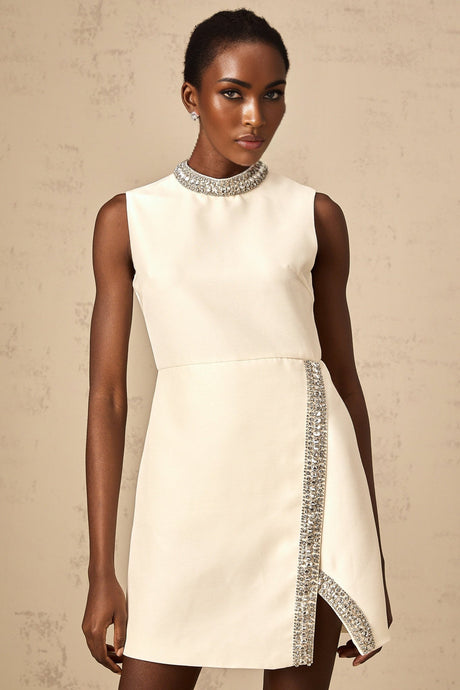A short white mini dress adorned with crystal embellishments featuring a fitted silhouette and Babette style design