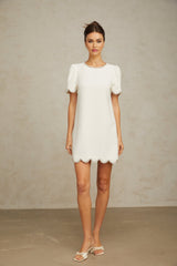 A short white mini dress adorned with crystal embellishments featuring a fitted silhouette and delicate detailing