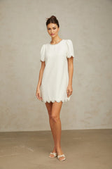 A short white mini dress adorned with crystal embellishments featuring a fitted silhouette and delicate sparkle details