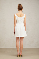 A short white mini dress adorned with crystal embellishments featuring a fitted silhouette and shimmering details
