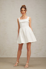 A short white mini dress adorned with crystal embellishments featuring a fitted silhouette and sparkling details throughout