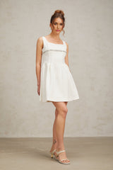 A short white mini dress adorned with crystal embellishments featuring a fitted silhouette and sparkling details throughout