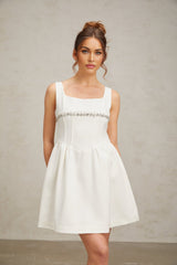 A short white mini dress adorned with crystal embellishments featuring a sleek and elegant design suitable for formal occasions