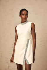 A short white mini dress adorned with crystal embellishments featuring a sleek and elegant design