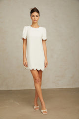 A short white mini dress adorned with crystal embellishments featuring a sleeveless design and a fitted silhouette