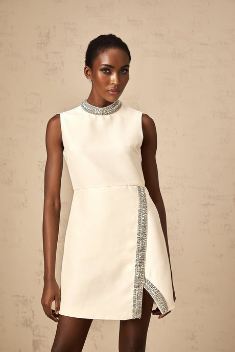 A short white mini dress adorned with sparkling crystal embellishments featuring a fitted silhouette and delicate details