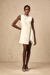 A short white mini dress adorned with sparkling crystal embellishments featuring a fitted silhouette and feminine design