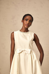 A short white mini dress with a bow accent featuring a fitted silhouette and named Isabelle