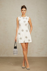 A short white mini dress with a delicate floral pattern adorned with crystal embellishments featuring a feminine silhouette and Coralie design