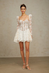 A short white mini dress with a fitted corset bodice made of floral lace featuring thin straps and a flared skirt