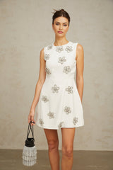 A short white mini dress with a floral pattern made of crystal embellishments covering the fabric featuring a feminine silhouette and delicate design