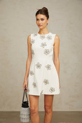 A short white mini dress with a floral pattern made of crystal embellishments featuring a delicate flower motif design
