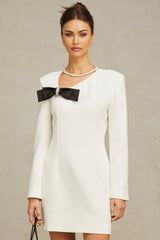A short white mini dress with an asymmetric hemline featuring a large bowknot detail on one side