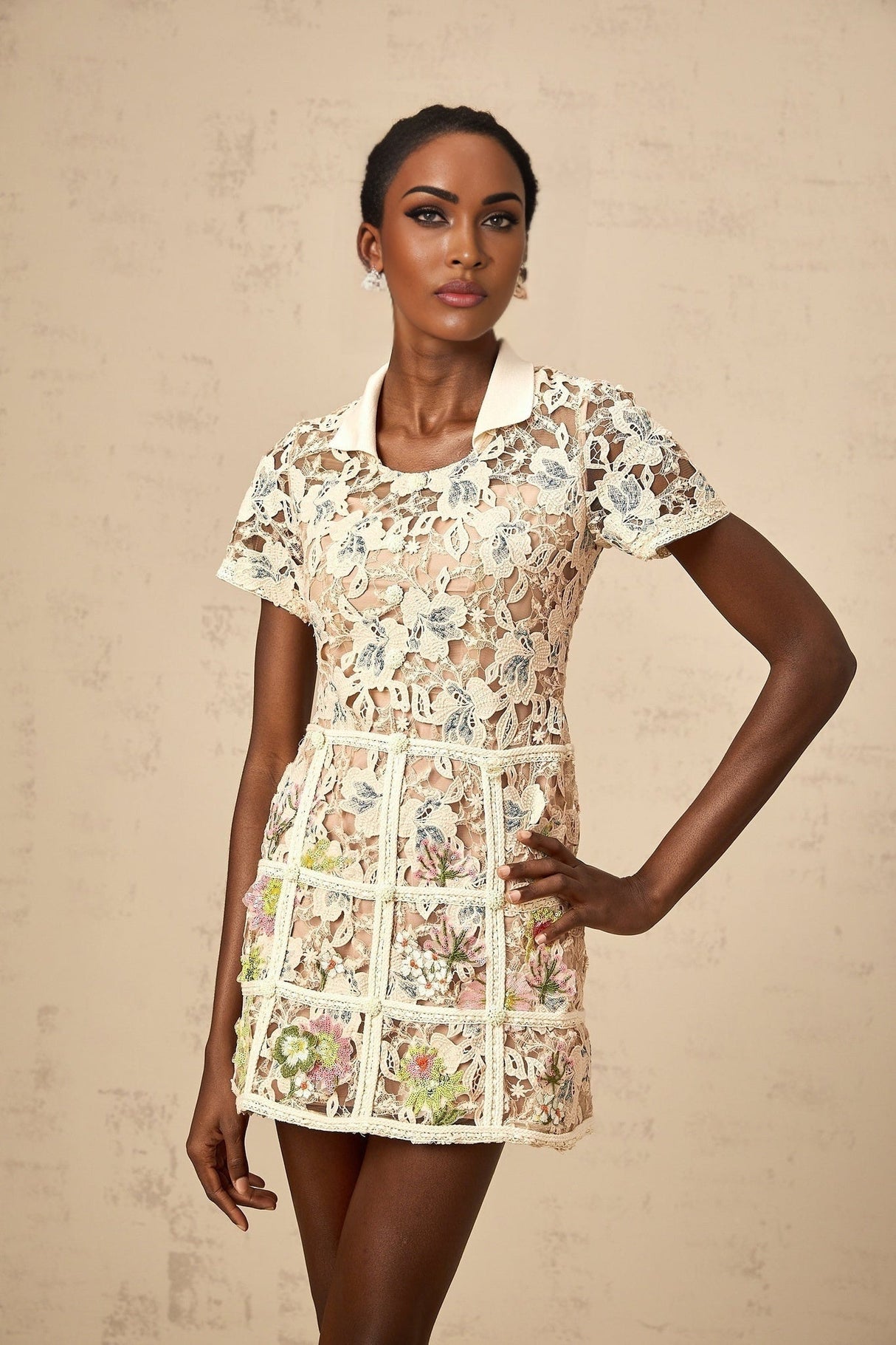 A short white mini dress with colorful floral embroidery adorning the fabric featuring a fitted bodice and flared skirt