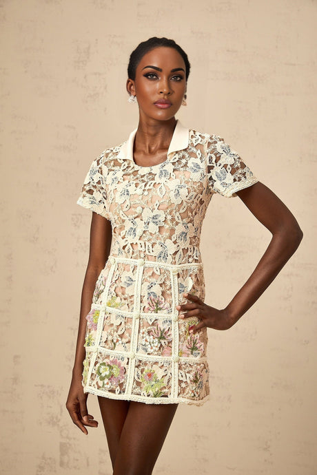 A short white mini dress with colorful floral embroidery adorning the fabric featuring a fitted bodice and flared skirt