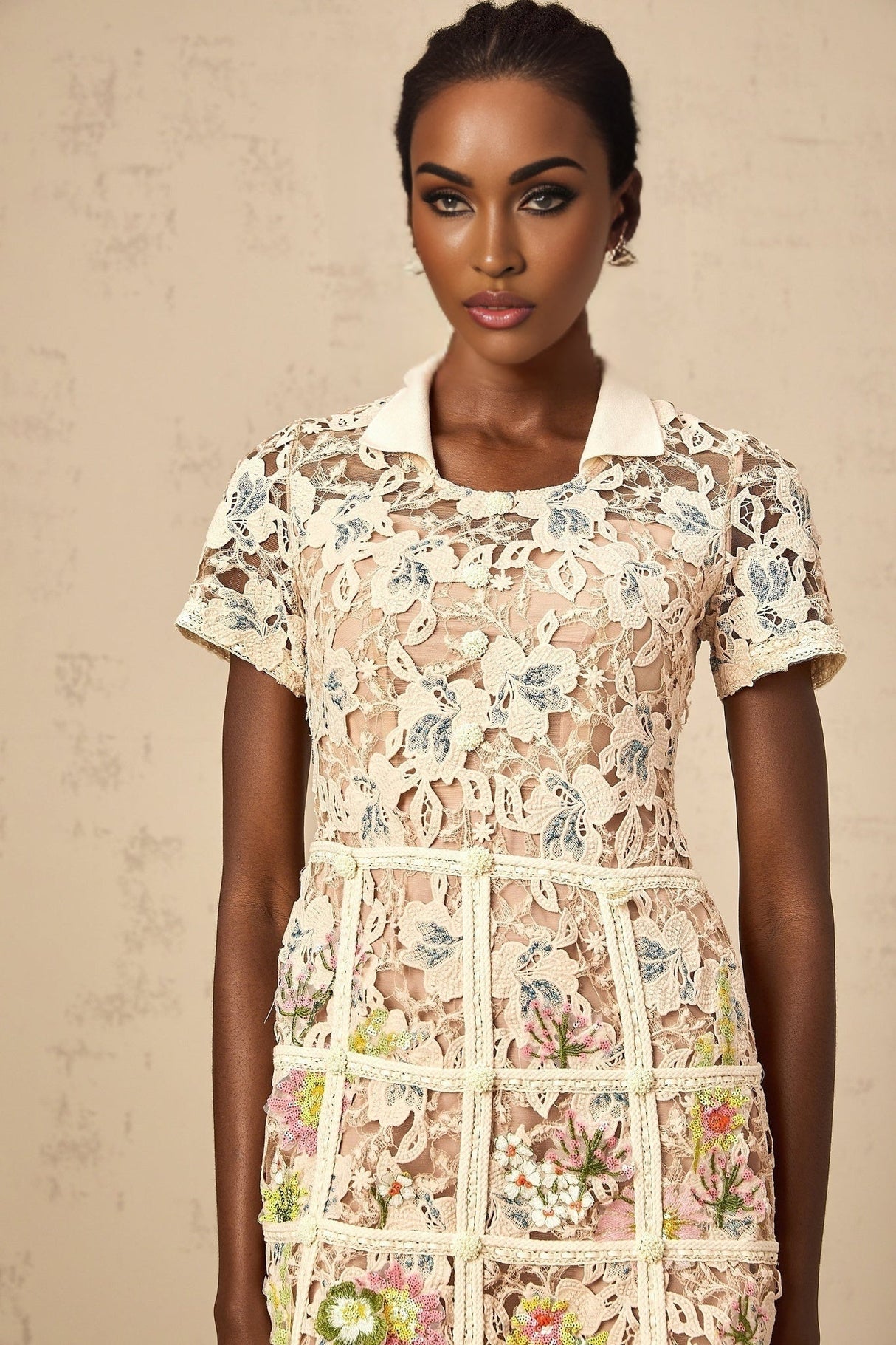 A short white mini dress with colorful floral embroidery details featuring a feminine silhouette and delicate straps