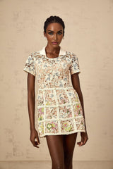 A short white mini dress with colorful floral embroidery featuring a fitted bodice and flared skirt